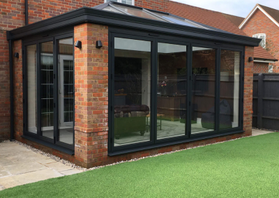 Daytime orangery exterior with a dark colour scheme facing outwards towards the garden